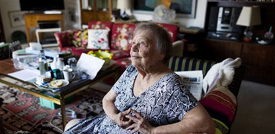 En ældre kvinde sidder i sit hjem og kigger op