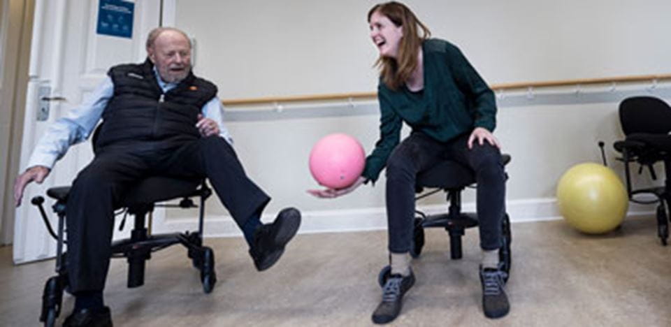 ældre herre laver øvelser med en bold med en kvinde 